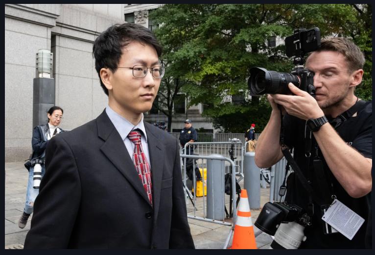 A person in a suit and tie with a cameraman taking a picture of himDescription automatically generated